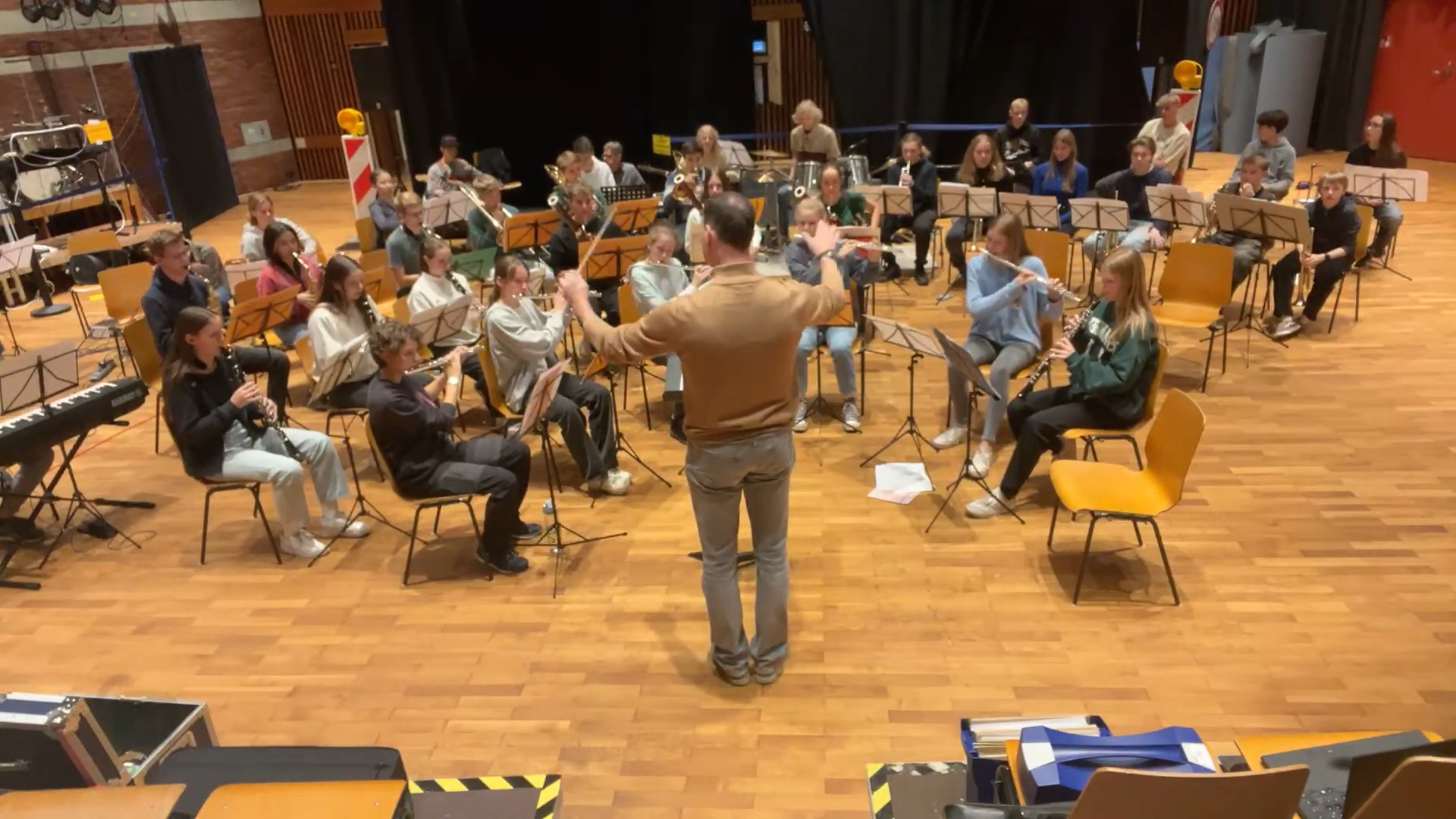 Jugendliche proben gemeinsam im Orchester, vor ihnen steht der Dirigent.